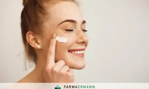 Donna sorridente applica latte detergente viso con la mano.