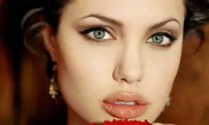 Primo piano di una donna con labbra carnose e occhi verde scuro penetranti, incorniciati da ciglia lunghe e folte.
