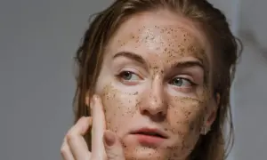 Donna si esfolia il viso con uno scrub, la pelle appare luminosa e rigenerata.