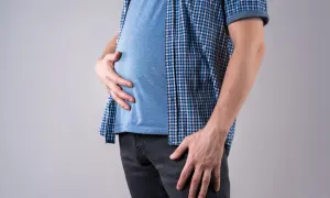 Uomo magro con pancia gonfia, che si tiene l'addome con le mani.