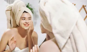 Ragazza con turbante applica una maschera sul viso, un gesto per come idratare la pelle e renderla luminosa.