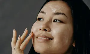 Una donna applica una crema sul viso, un gesto che racchiude l'essenza di che cos'è la skincare: cura e benessere per la pelle.
