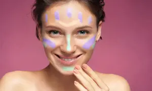 Ragazza sorridente con correttori colorati sul viso, un esempio visivo per capire come scegliere il correttore giusto per ogni imperfezione.