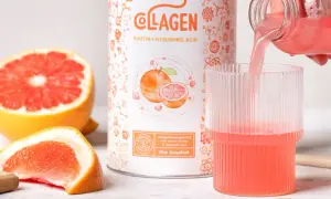 Il collagene in polvere al pompelmo rosa viene versato in un bicchiere, con fette di pompelmo fresco intorno.