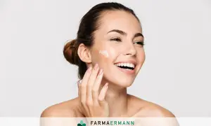 Donna sorridente applica crema sul viso. Il doposole serve a lenire e idratare la pelle dopo l'esposizione al sole, mantenendola morbida e sana.