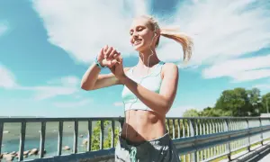 Donna bionda con smartwatch e auricolari controlla i suoi progressi, ideale per dimagrire meglio correre o camminare.
