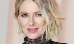 Primo piano di una donna con trucco palpebra cadente, labbra rosa e capelli biondi mossi.