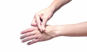 Dita che pizzicano la pelle del dorso della mano, mostrando la sua elasticità.