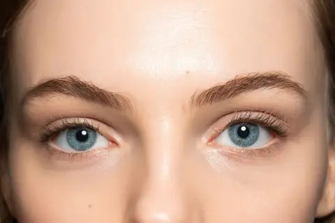 Occhi azzurri luminosi con un trucco leggero che ne esalta la bellezza naturale. Ciglia lunghe e definite.