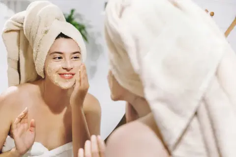 Ragazza con turbante applica una maschera sul viso, un gesto per come idratare la pelle e renderla luminosa.