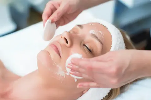Una donna riceve un trattamento viso. La frequenza ideale per la pulizia del viso dipende dal tipo di pelle e dalle esigenze individuali.