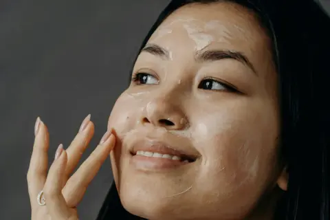 Una donna applica una crema sul viso, un gesto che racchiude l'essenza di che cos'è la skincare: cura e benessere per la pelle.