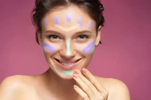 Ragazza sorridente con correttori colorati sul viso, un esempio visivo per capire come scegliere il correttore giusto per ogni imperfezione.
