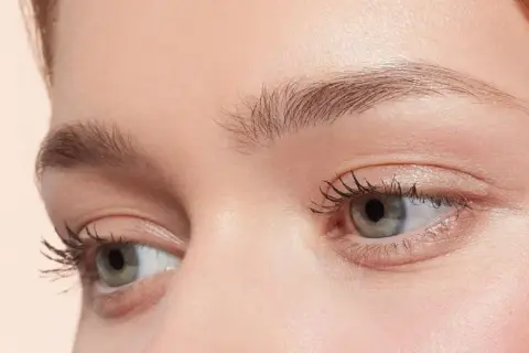 Occhi verdi con ciglia lunghe e folte, sopracciglia curate e un tocco di blush. Un look make up nude che esalta la bellezza naturale.