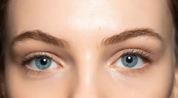 Occhi azzurri luminosi con un trucco leggero che ne esalta la bellezza naturale. Ciglia lunghe e definite.