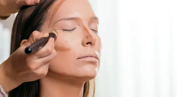 Applicazione di prodotto per lo schema contouring viso con pennello, definendo zigomi e naso.