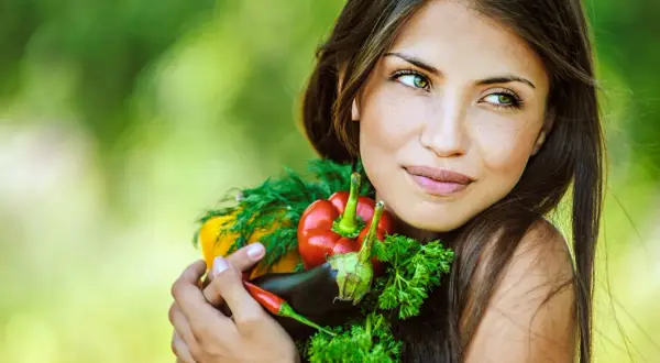 Segreti per come avere una pelle perfetta: una donna abbraccia verdure fresche, simbolo di benessere e bellezza naturale.