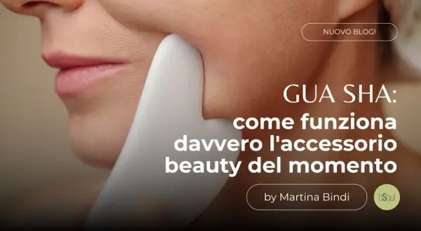 Un primo piano del viso di una donna con uno strumento **gua sha viso** bianco che scivola sulla sua guancia. Testo: "GUA SHA: come funziona davvero l'accessorio beauty del momento".
