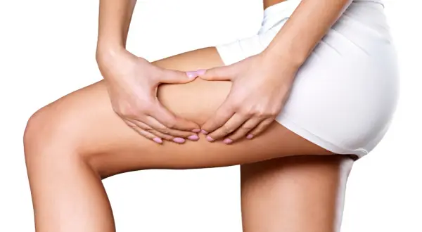 Mani che stringono la coscia, mostrando la texture della pelle. Un massaggio anticellulite doloroso per combattere gli inestetismi.