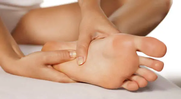 Mani che massaggiano un piede, evidenziando i benefici del massaggio piedi per il benessere e il rilassamento.