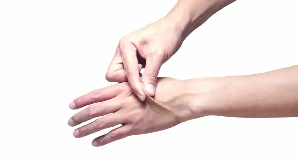Dita che pizzicano la pelle del dorso della mano, mostrando la sua elasticità.