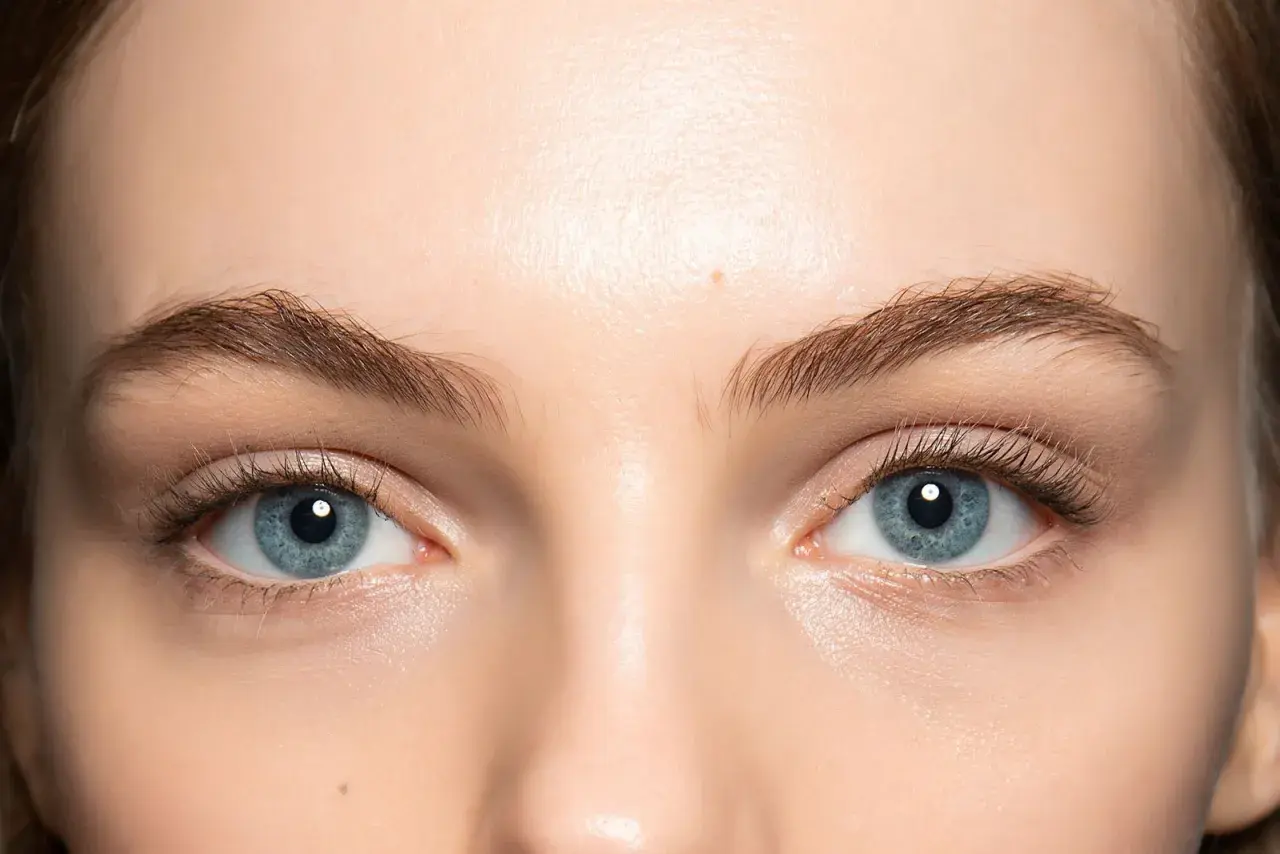 Occhi azzurri luminosi con un trucco leggero che ne esalta la bellezza naturale. Ciglia lunghe e definite.