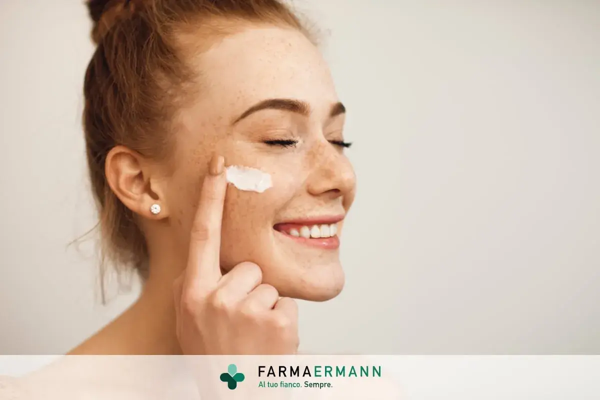 Donna sorridente applica latte detergente viso con la mano.