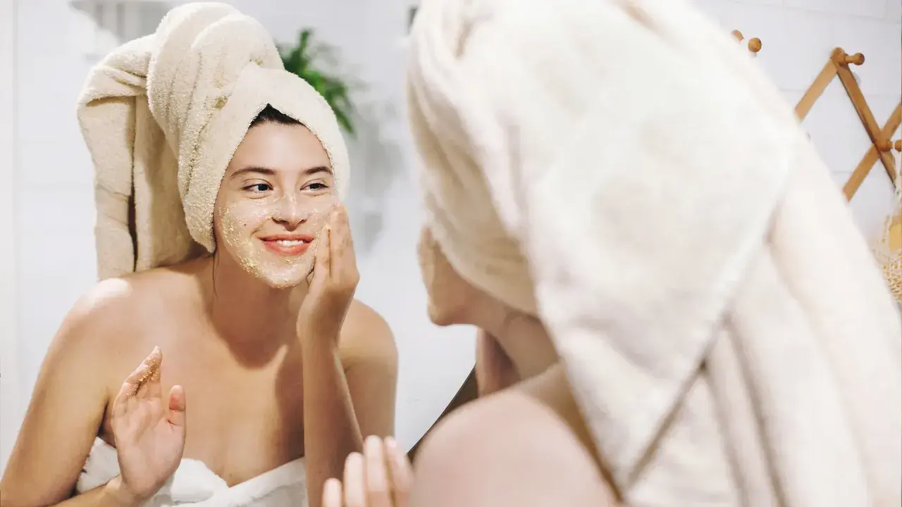 Ragazza con turbante applica una maschera sul viso, un gesto per come idratare la pelle e renderla luminosa.