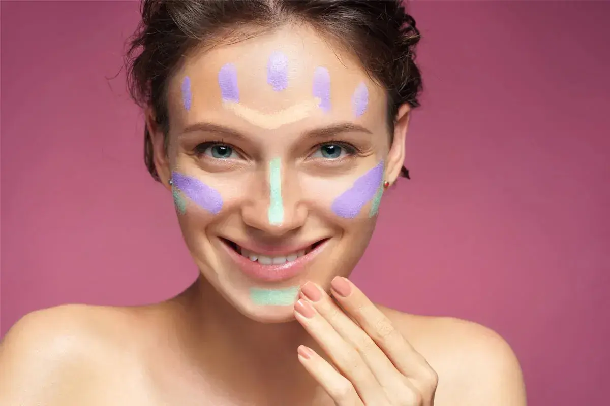 Ragazza sorridente con correttori colorati sul viso, un esempio visivo per capire come scegliere il correttore giusto per ogni imperfezione.