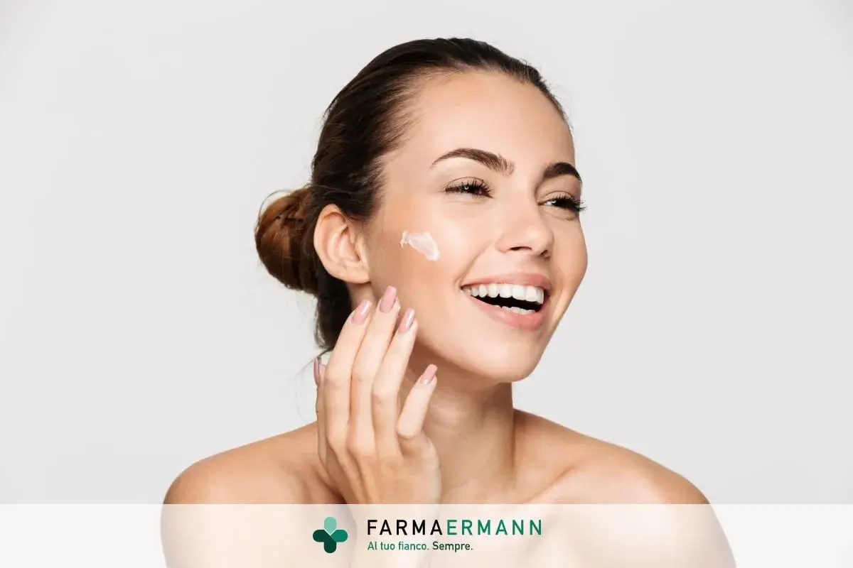 Donna sorridente applica crema sul viso. Il doposole serve a lenire e idratare la pelle dopo l'esposizione al sole, mantenendola morbida e sana.