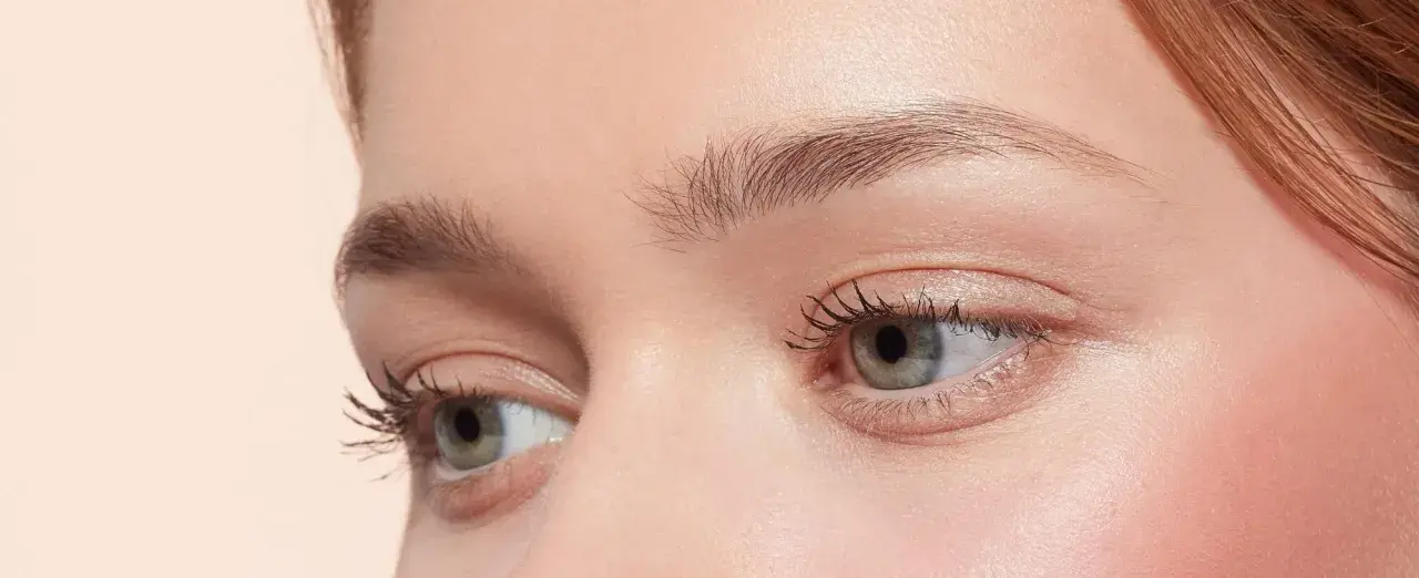 Occhi verdi con ciglia lunghe e folte, sopracciglia curate e un tocco di blush. Un look make up nude che esalta la bellezza naturale.
