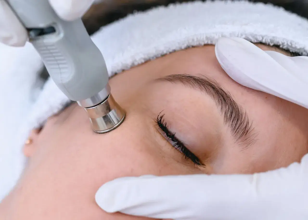Trattamento viso con manipolo per migliorare l'elasticità della pelle. Mani guantate e fascia per capelli.