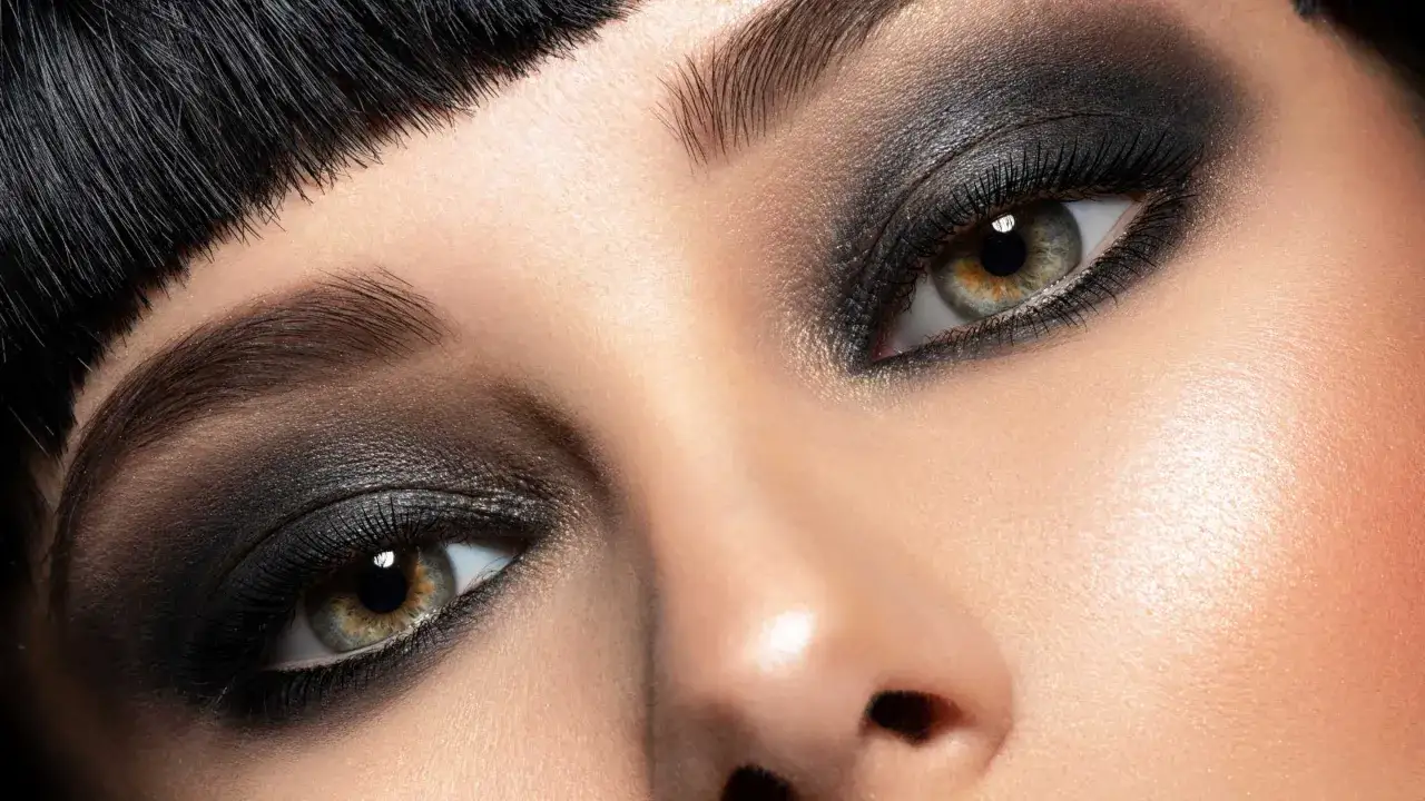 Occhi intensi con un audace trucco occhi nero, ciglia lunghe e sopracciglia definite.