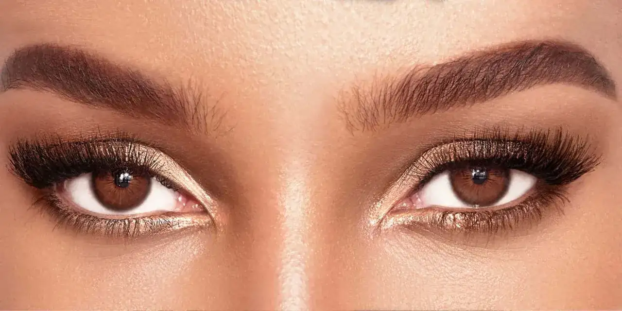 Occhi neri donna, con ciglia lunghe e folte, trucco dorato e sopracciglia definite. Uno sguardo intenso e magnetico.