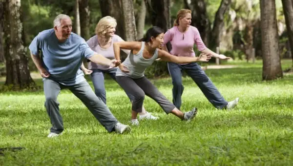 Gruppo di persone pratica tai chi in un parco, con movimenti fluidi e concentrati tra gli alberi.