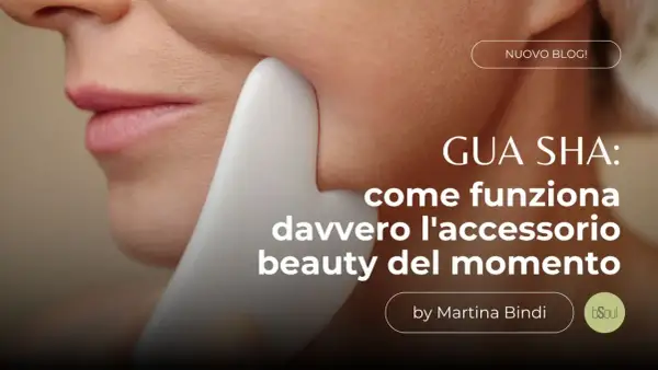 Un primo piano del viso di una donna con uno strumento **gua sha viso** bianco che scivola sulla sua guancia. Testo: "GUA SHA: come funziona davvero l'accessorio beauty del momento".
