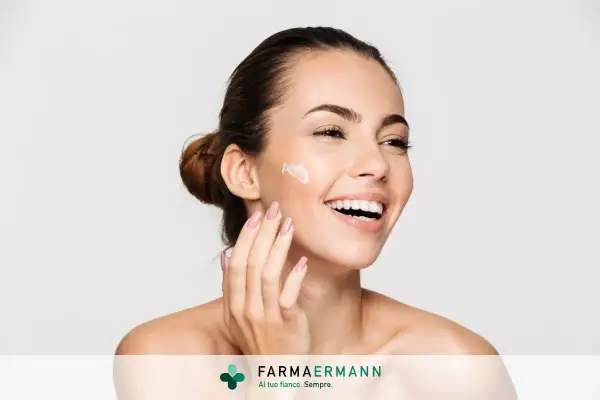 Donna sorridente applica crema sul viso. Il doposole serve a lenire e idratare la pelle dopo l'esposizione al sole, mantenendola morbida e sana.