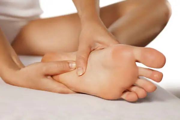 Mani che massaggiano un piede, evidenziando i benefici del massaggio piedi per il benessere e il rilassamento.